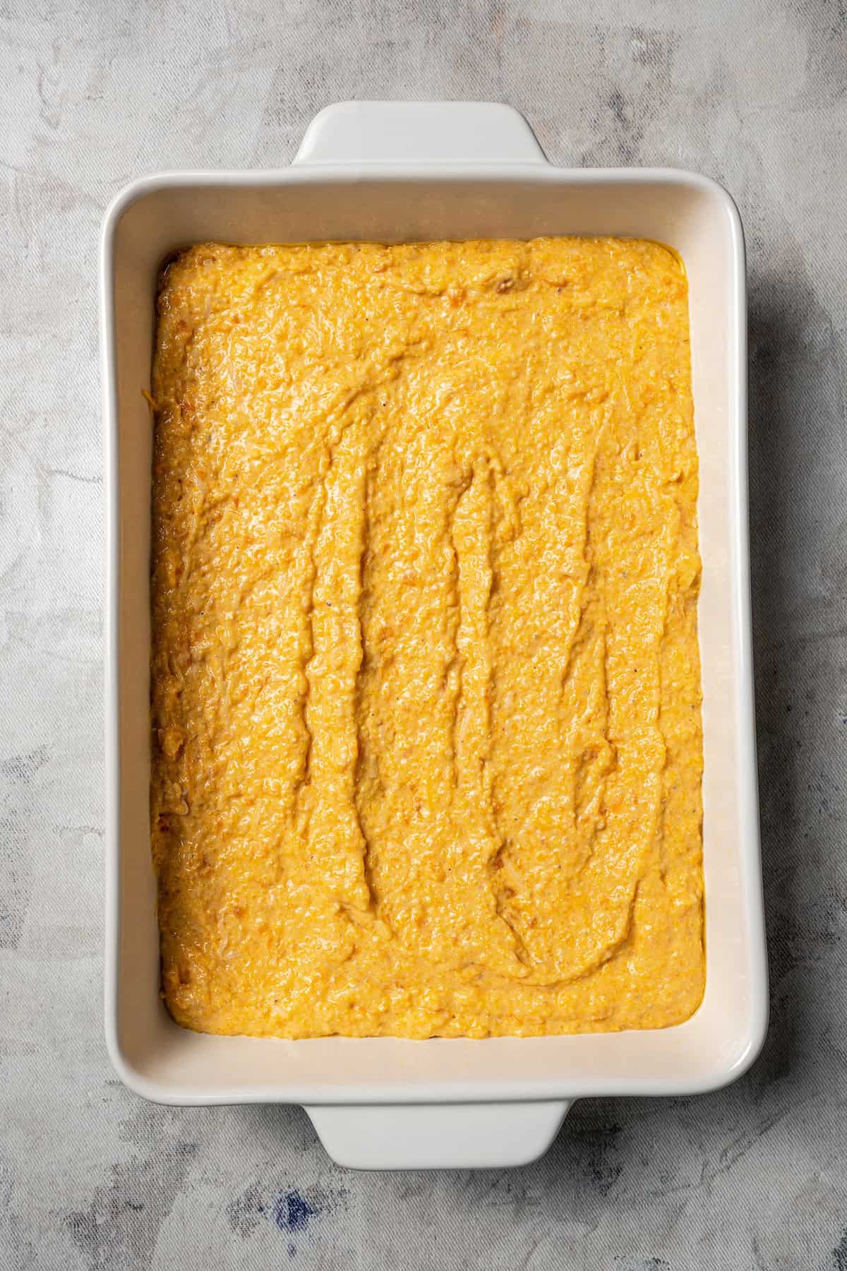 Sweet potato cornbread batter spread into a casserole dish.