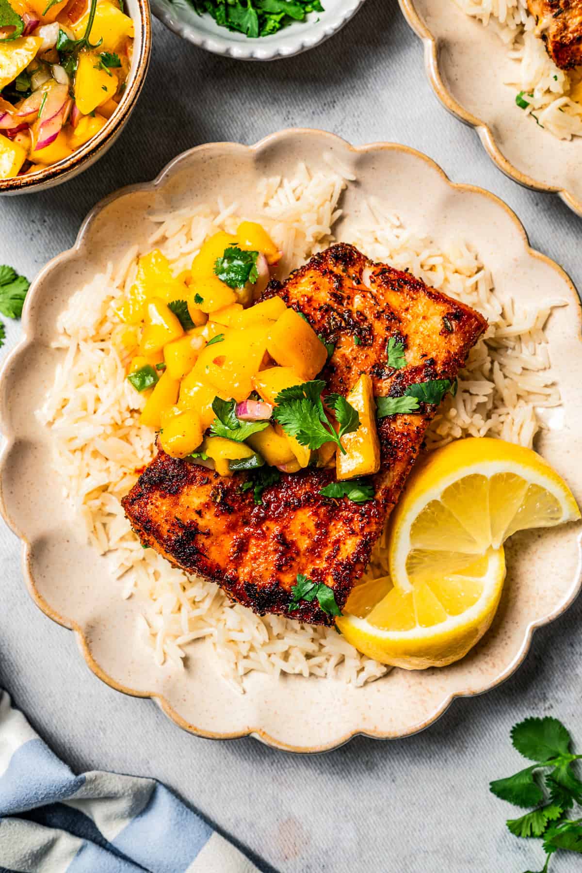 Blackened mahi mahi is a quick fish dish packed with Southern flavor thanks to a spicy homemade Cajun seasoning rub. Great for weeknights! Mahi mahi served over rice, garnished with mango salsa and lemon wedges on a plate.
