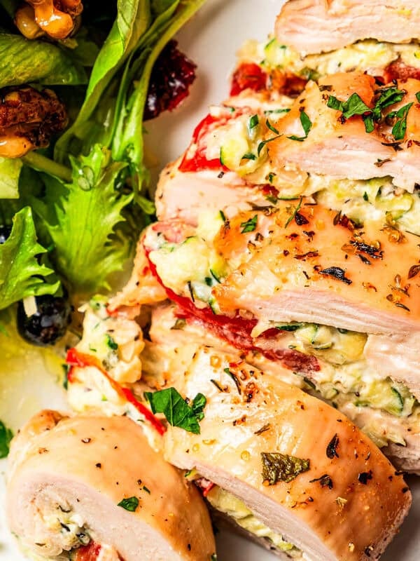 Sliced stuffed chicken breast served on a plate with a side salad. Photo and recipe on diethood.com