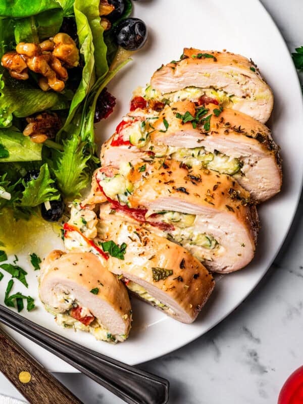 Sliced stuffed chicken breast served on a plate with a side salad. Photo and recipe on diethood.com
