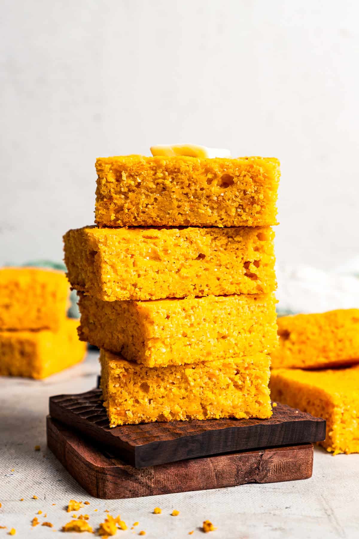 Four slices of sweet potato cornbread stacked, topped with a pat of butter.
