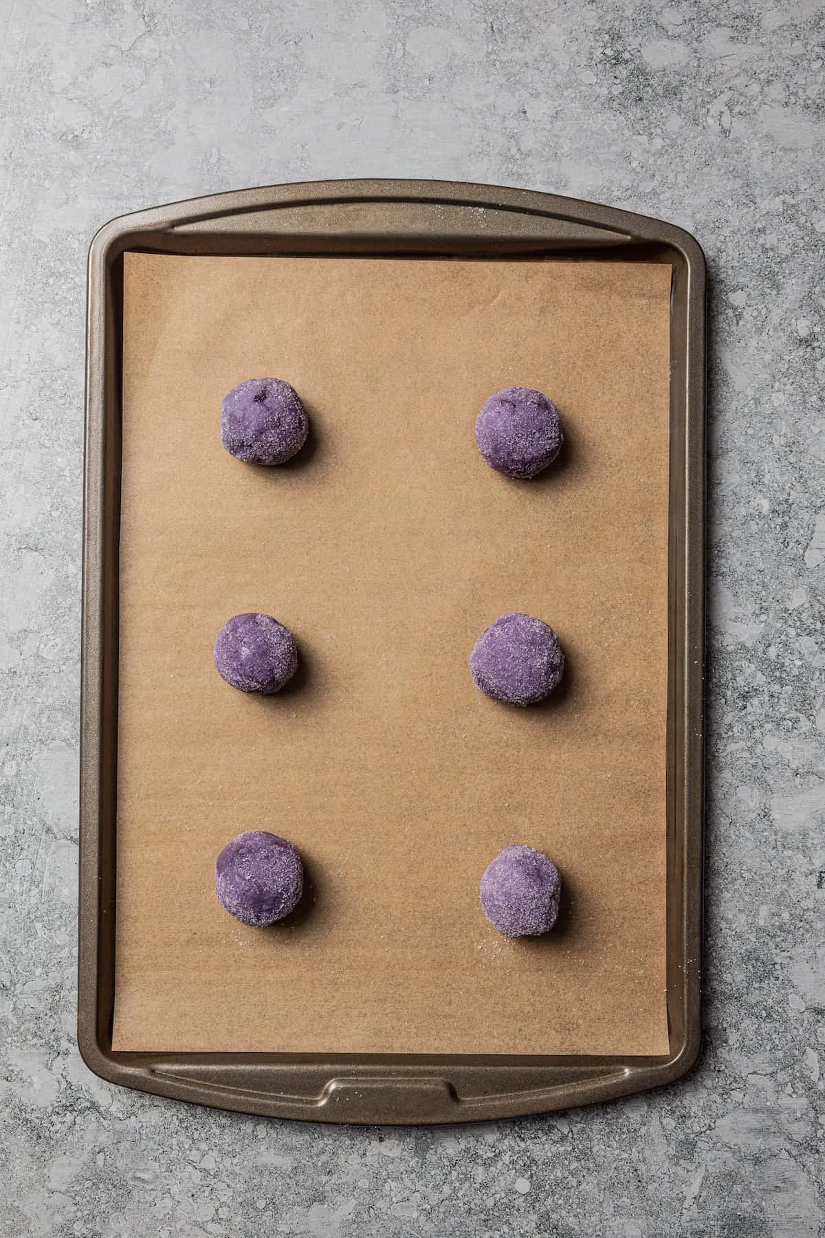 Blueberry cookie dough balls on a lined baking sheet.