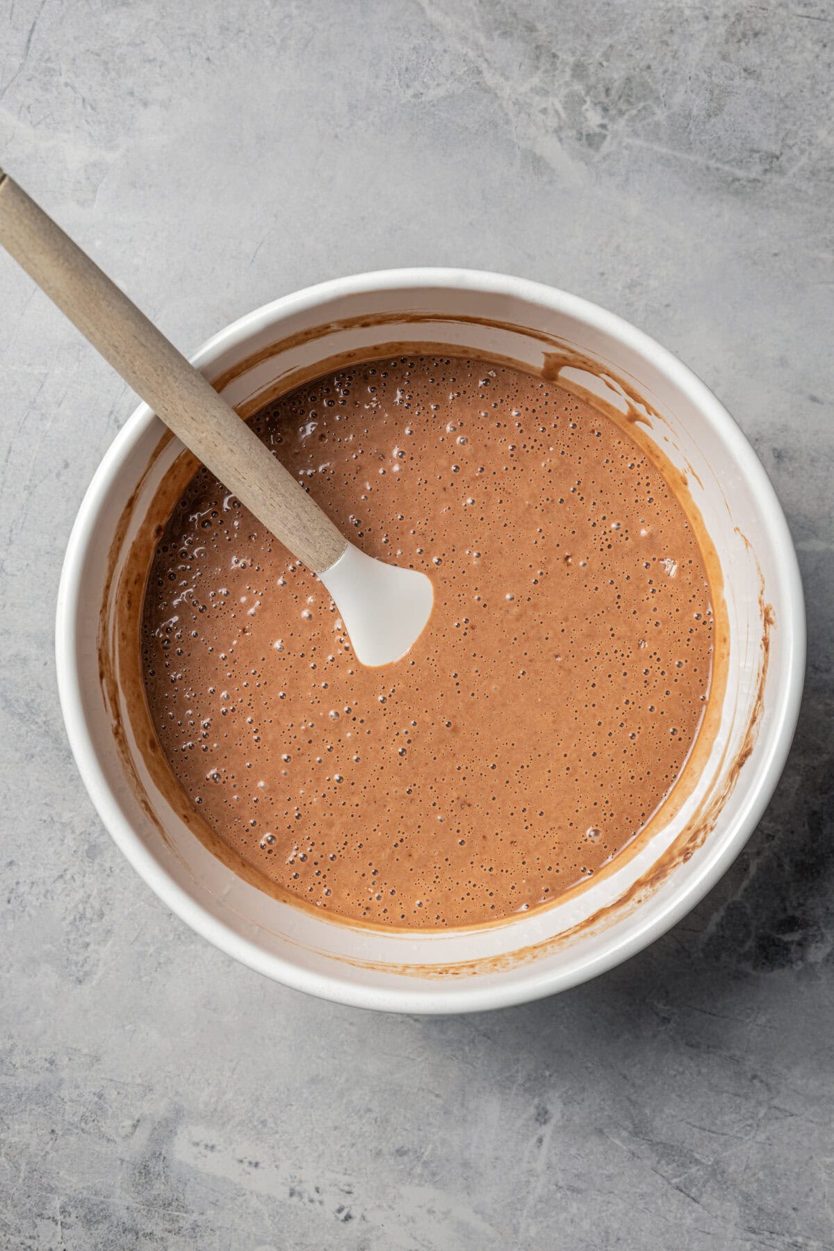 Chocolate pancake batter in a large bowl with a spoon.
