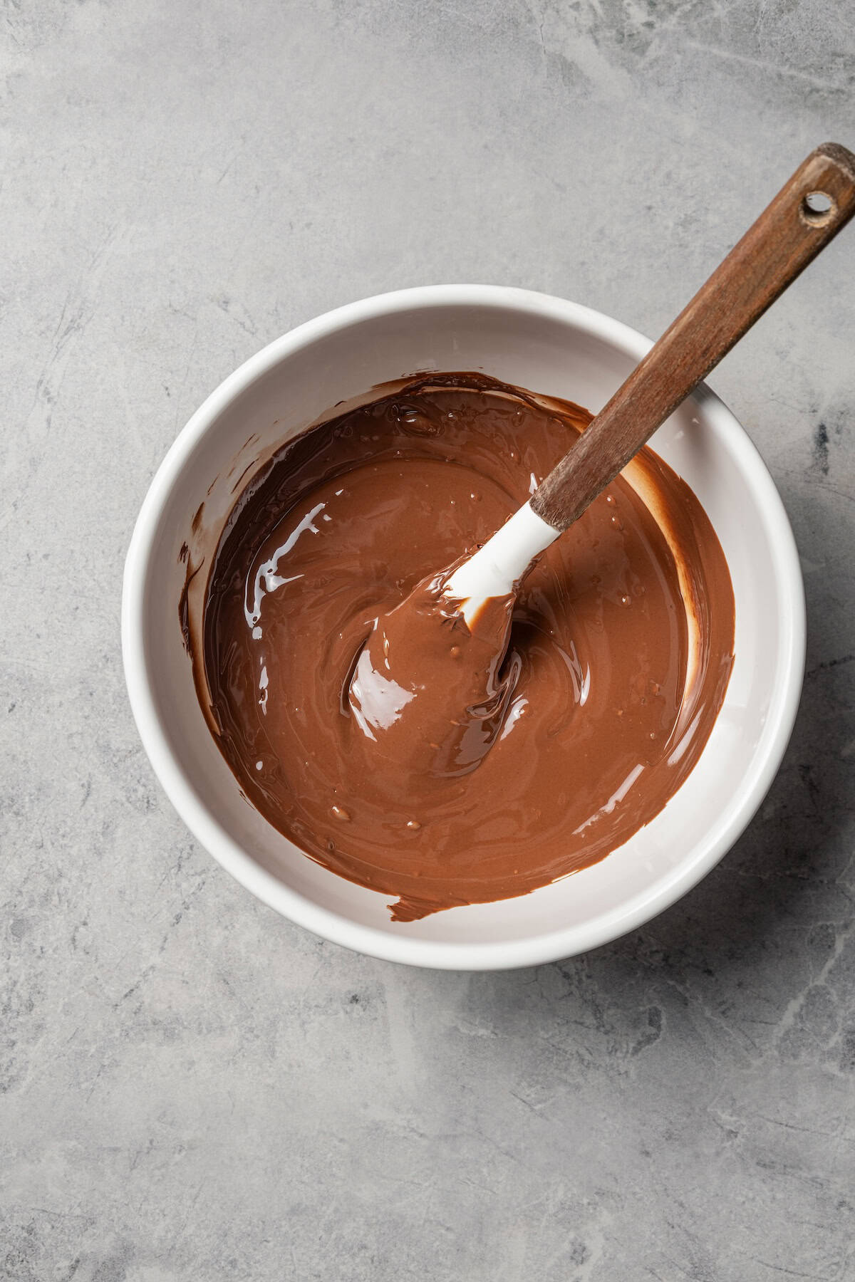 Make fudgy Nutella brownies by whipping eggs and adding Nutella. That's it! These brownies are extra chocolatey and naturally gluten-free. Nutella brownie batter in a white bowl with a spoon.