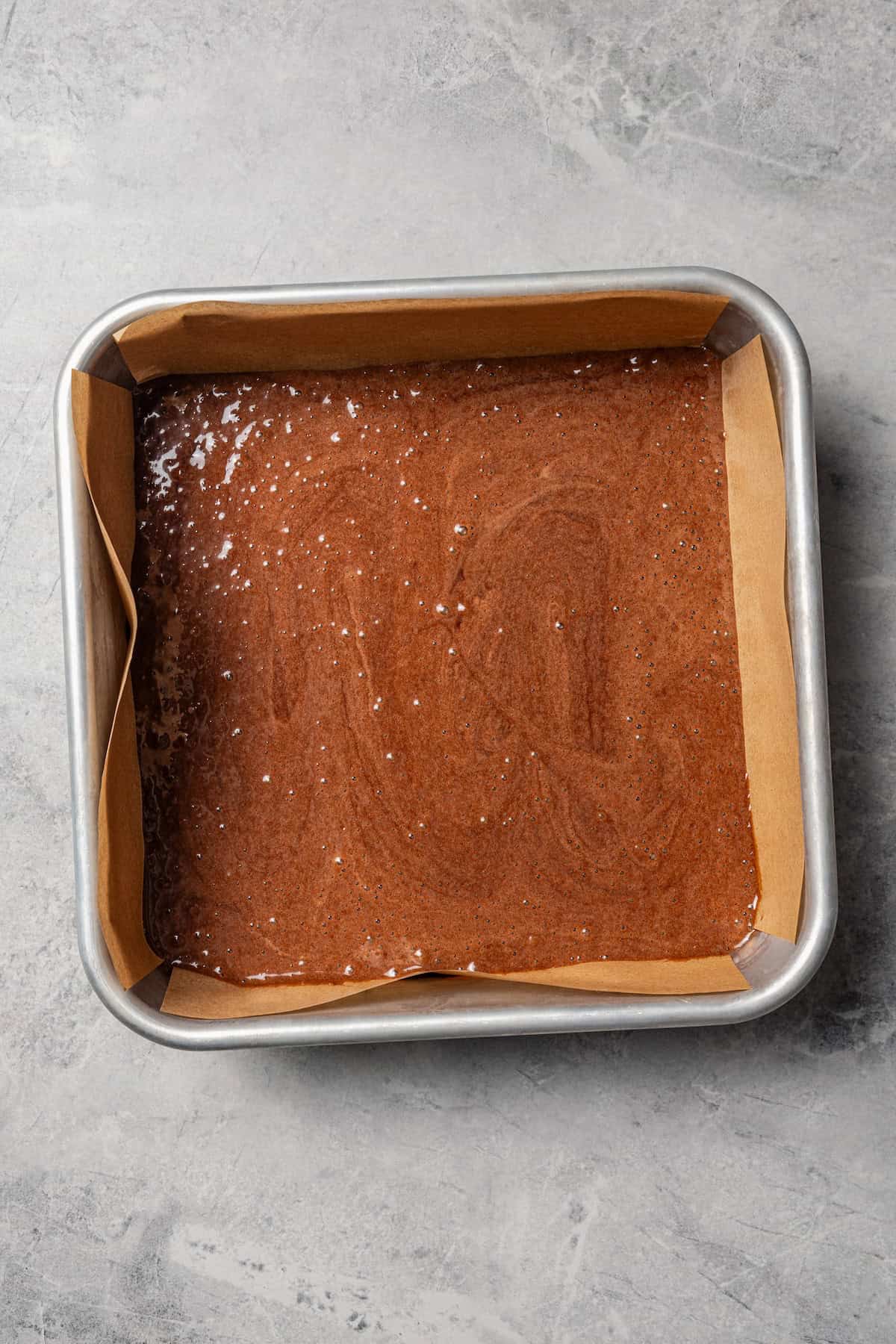 Make fudgy Nutella brownies by whipping eggs and adding Nutella. That's it! These brownies are extra chocolatey and naturally gluten-free. Nutella brownie batter in a lined square pan.