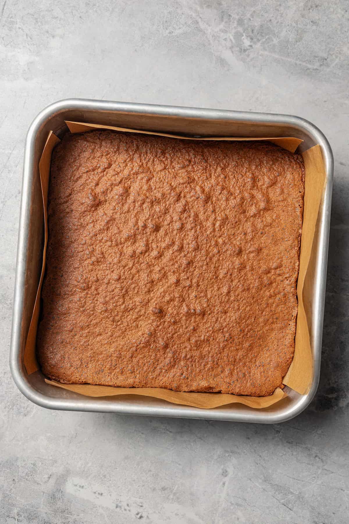Make fudgy Nutella brownies by whipping eggs and adding Nutella. That's it! These brownies are extra chocolatey and naturally gluten-free. Baked Nutella brownies in a lined square pan.