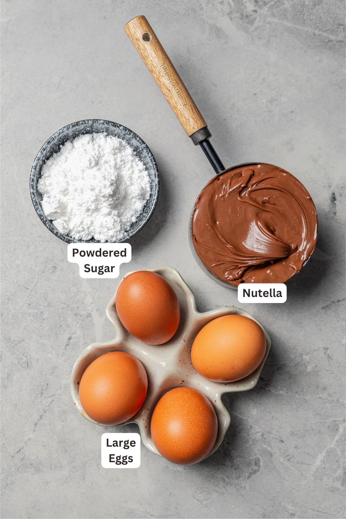Make fudgy Nutella brownies by whipping eggs and adding Nutella. That's it! These brownies are extra chocolatey and naturally gluten-free. Nutella brownie ingredients with text labels overlaying each ingredient.