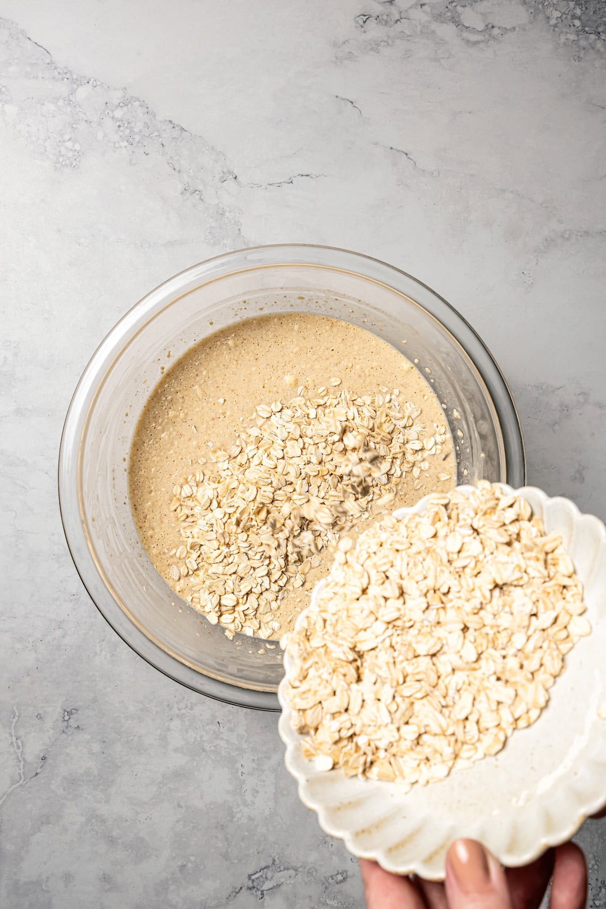 This baked oatmeal is loaded with protein from wholesome oats, almond butter, eggs, and protein powder. It's delicious, swirled with a juicy berry compote. Oats being added to a bowl of wet ingredients.