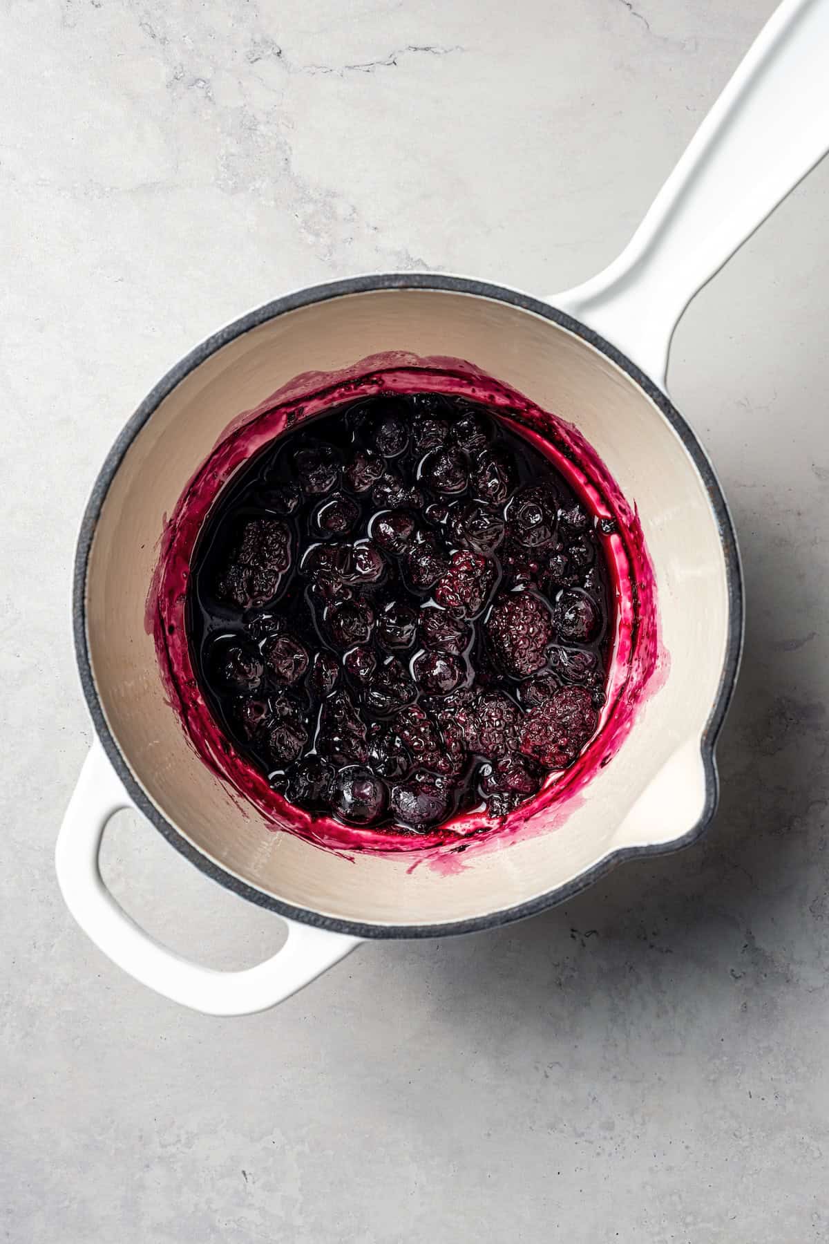 This baked oatmeal is loaded with protein from wholesome oats, almond butter, eggs, and protein powder. It's delicious, swirled with a juicy berry compote. Berry compote in a saucepan.