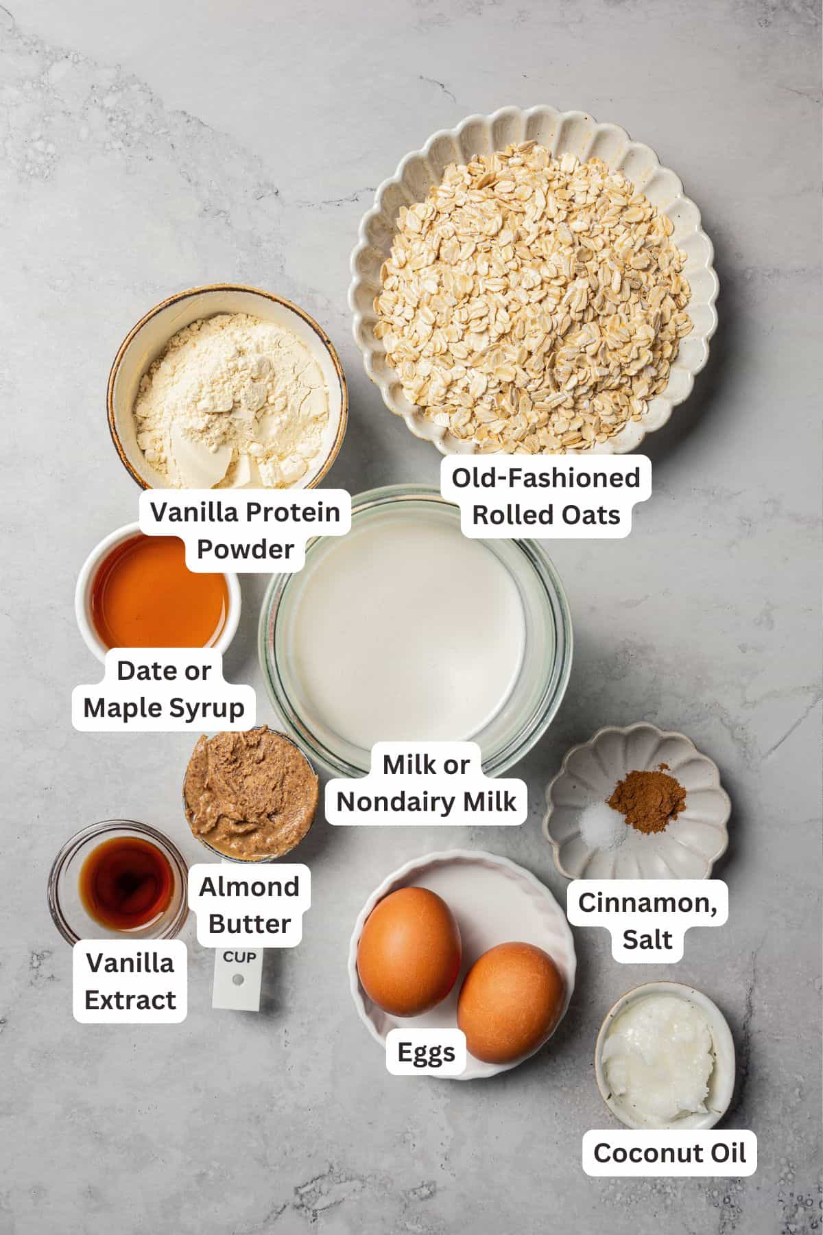 This baked oatmeal is loaded with protein from wholesome oats, almond butter, eggs, and protein powder. It's delicious, swirled with a juicy berry compote. Protein baked oatmeal ingredients with text labels overlaying each ingredient.