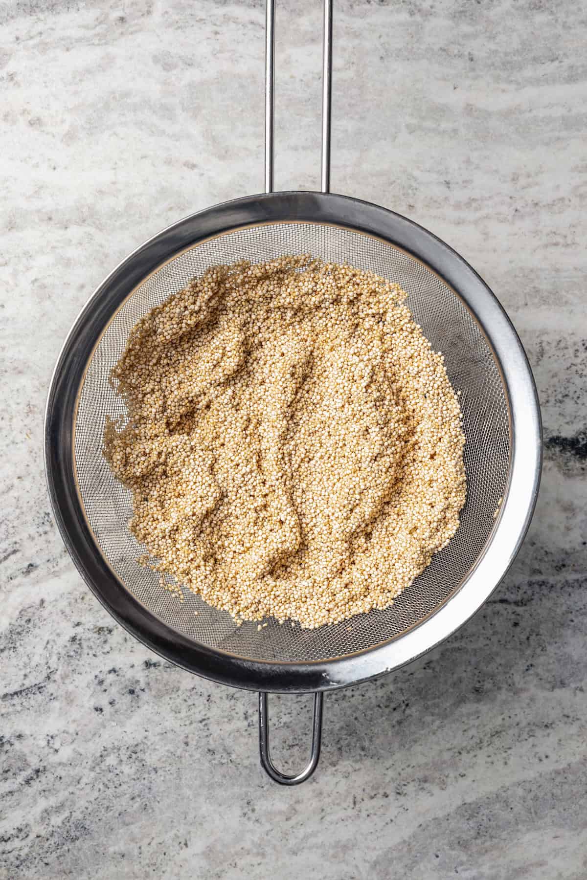 Strained quinoa in a mesh sieve.