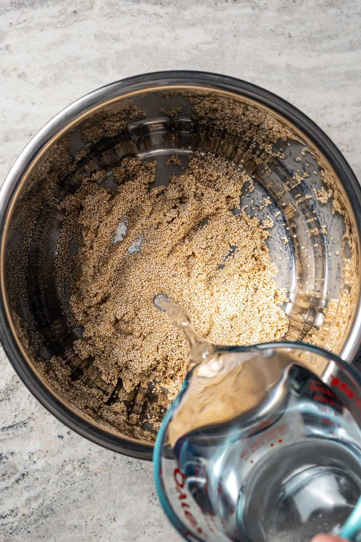 Water being poured over raw quinoa inside the Instant Pot.