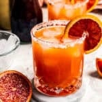 Blood orange margaritas garnished with a salt rim and a slice of orange.