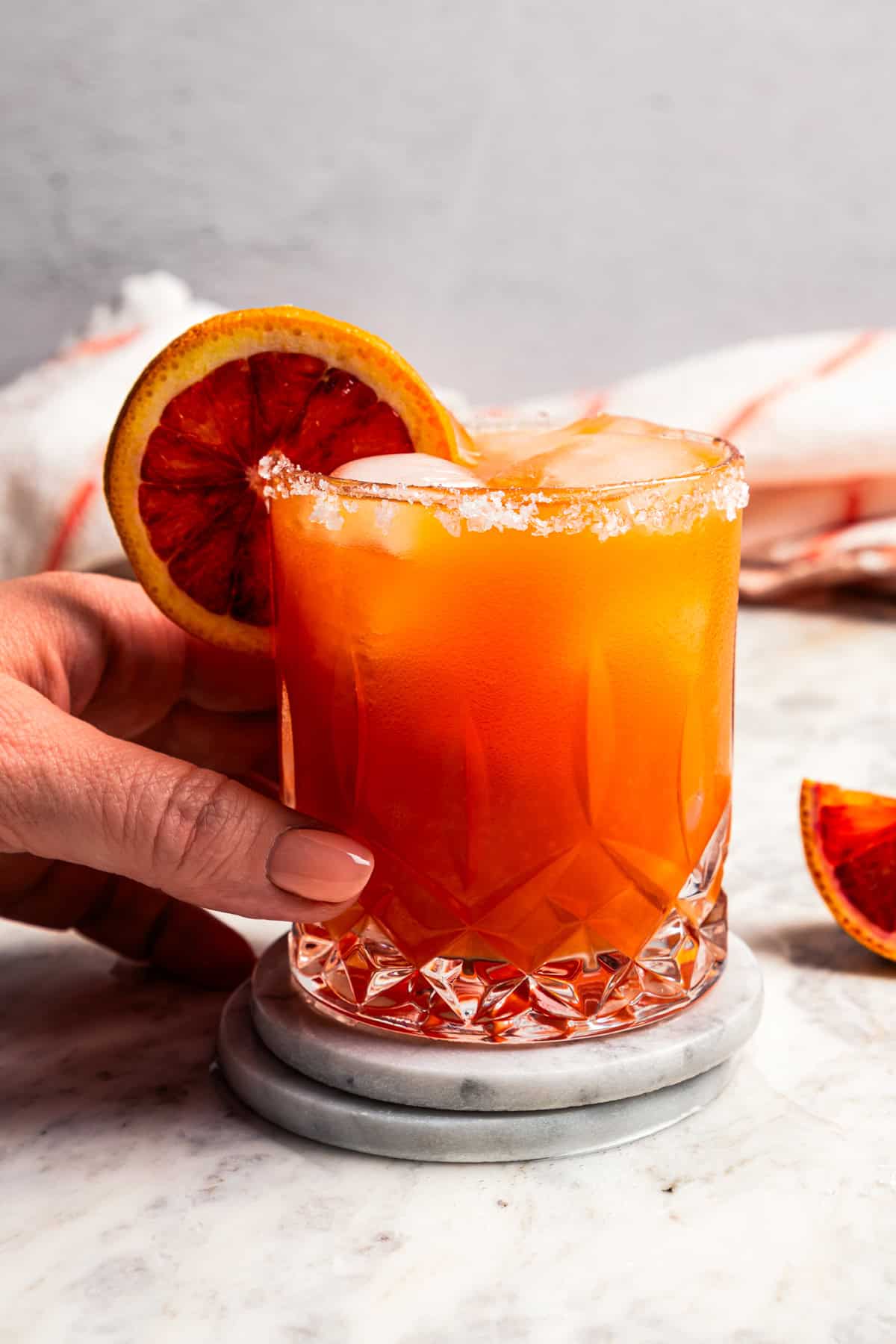 A hand holding a glass of margarita.