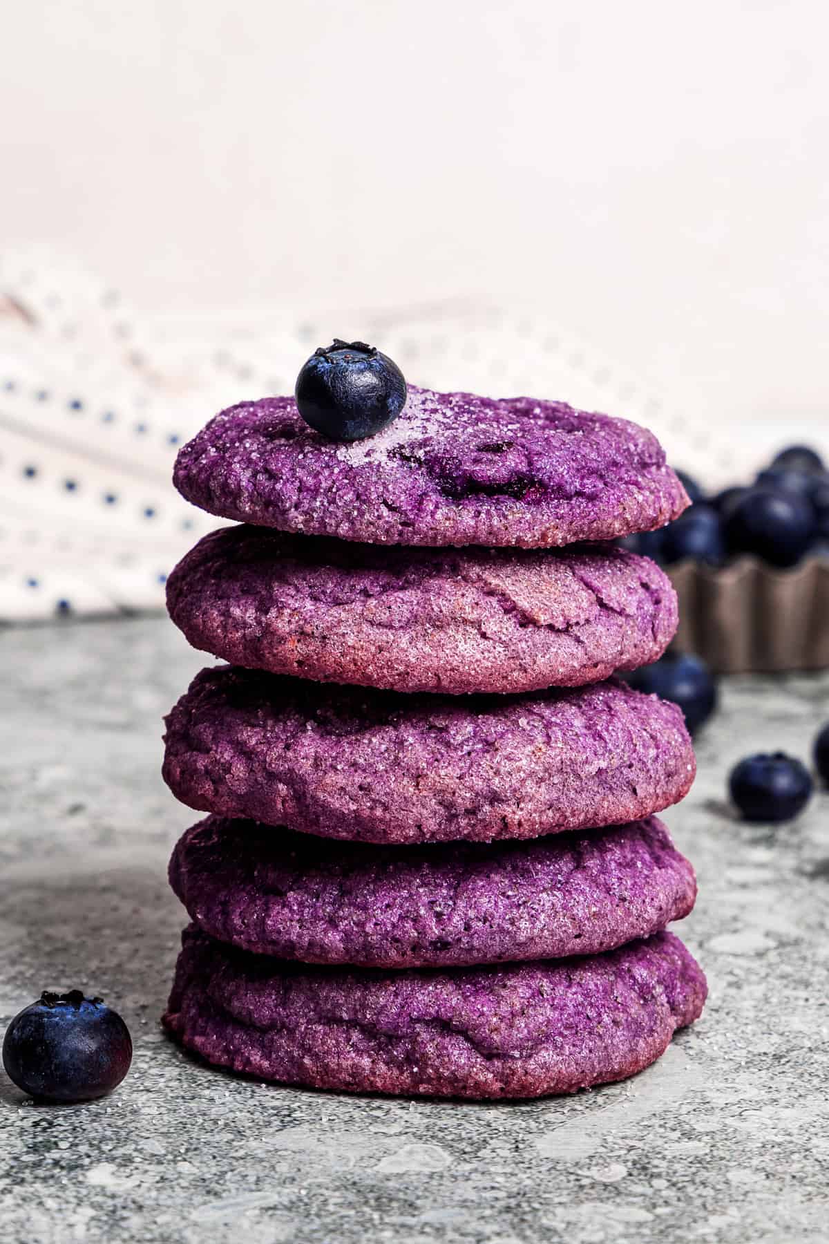 Blueberry cookies stacked on a countertop.