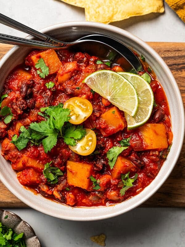 A bowl of butternut squash chili set on a wooden board.