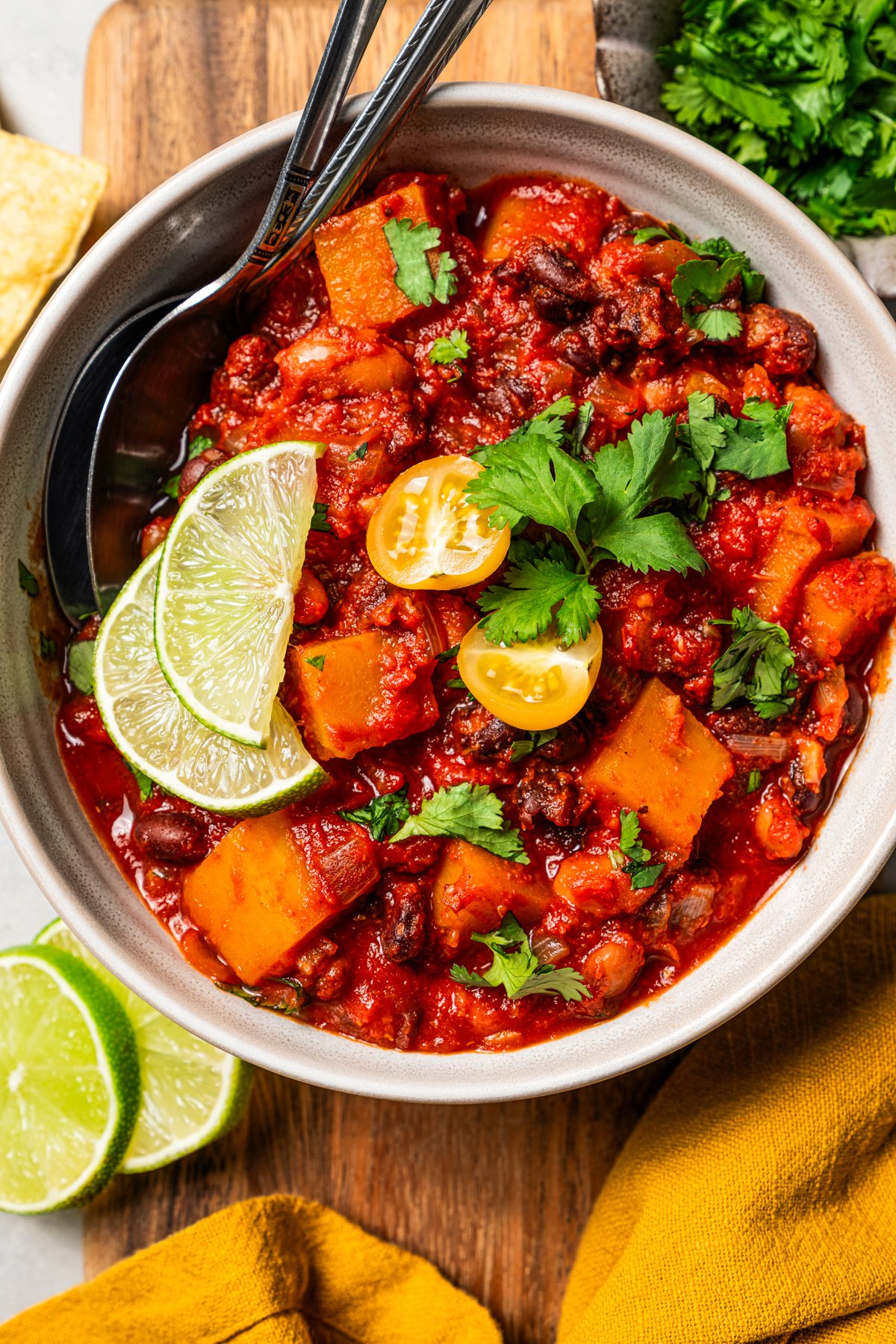 A bowl of butternut squash chili garnished with lime wedges.