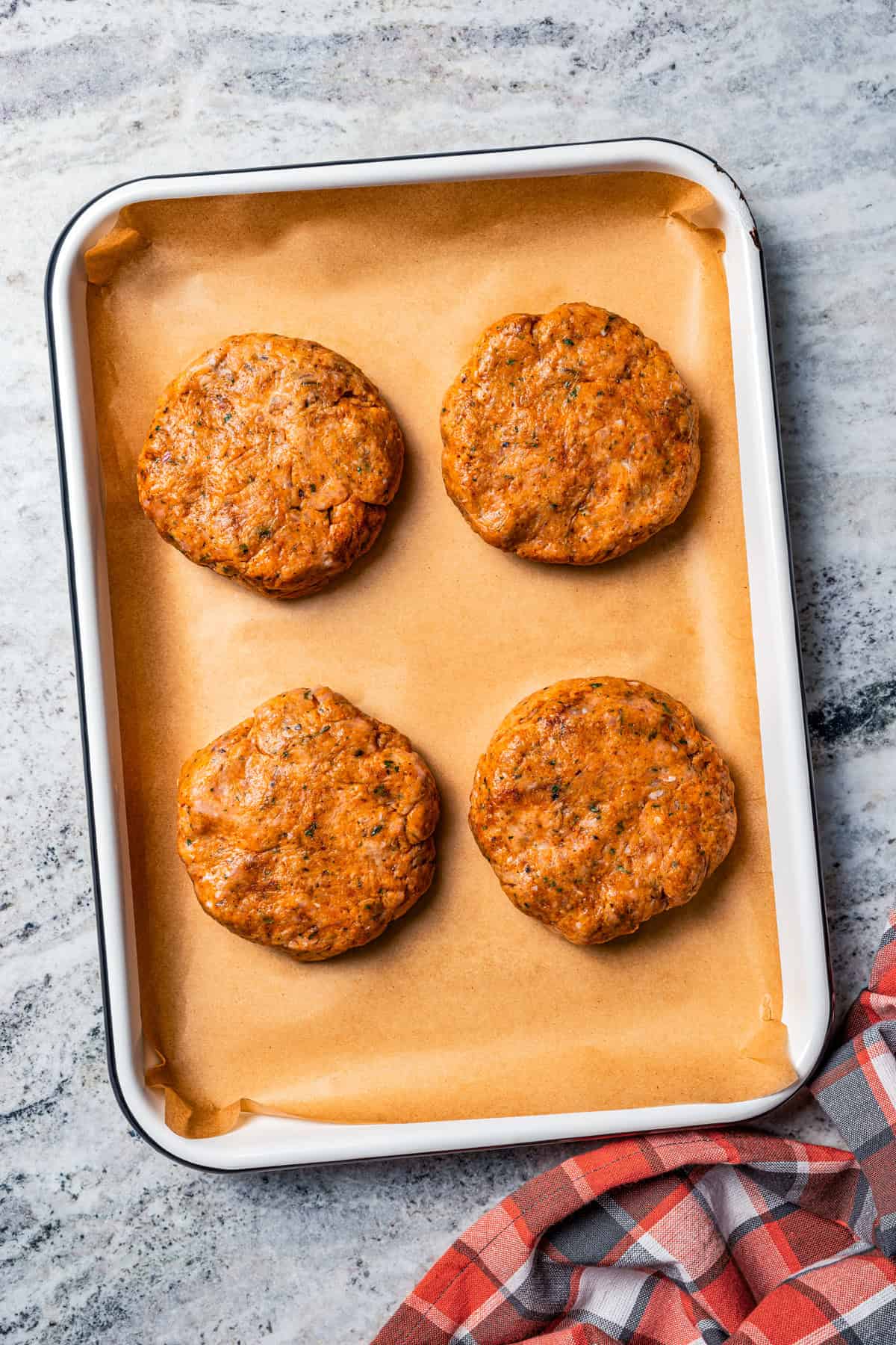 Chicken patties on a parchment-lined baking sheet.