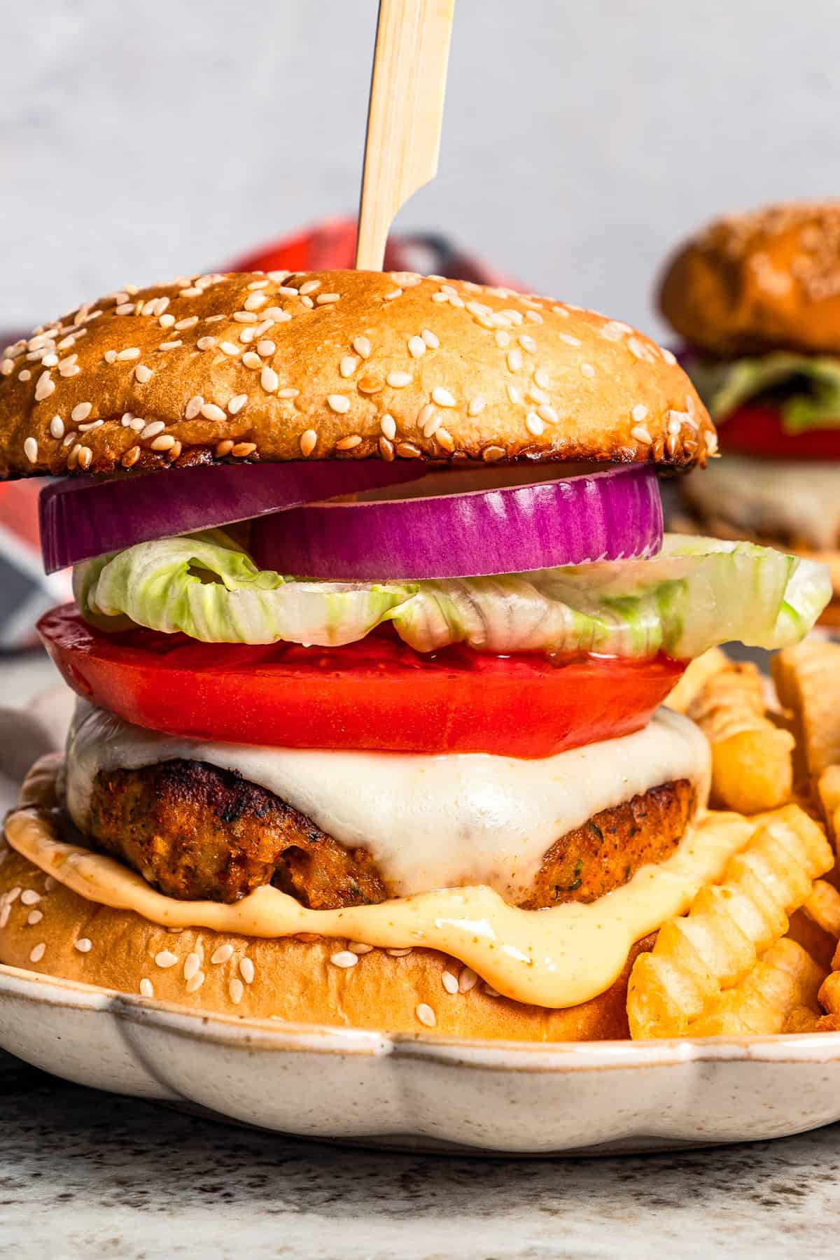 A chicken burger next to crinkle-cut French fries on a plate.