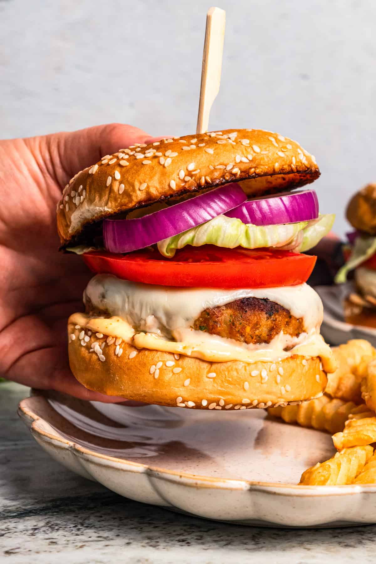 A hand holding up a homemade chicken burger by diethood.com.