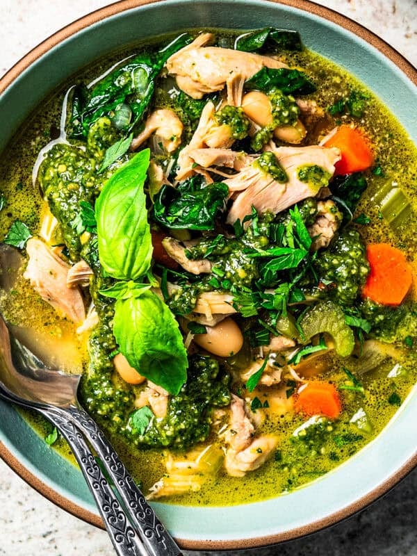 Chicken and white bean soup in a bowl, garnished with basil leaves.