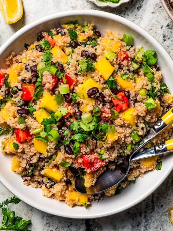 Overhead view of quinoa black bean salad in a large serving bowl with salad tongs.