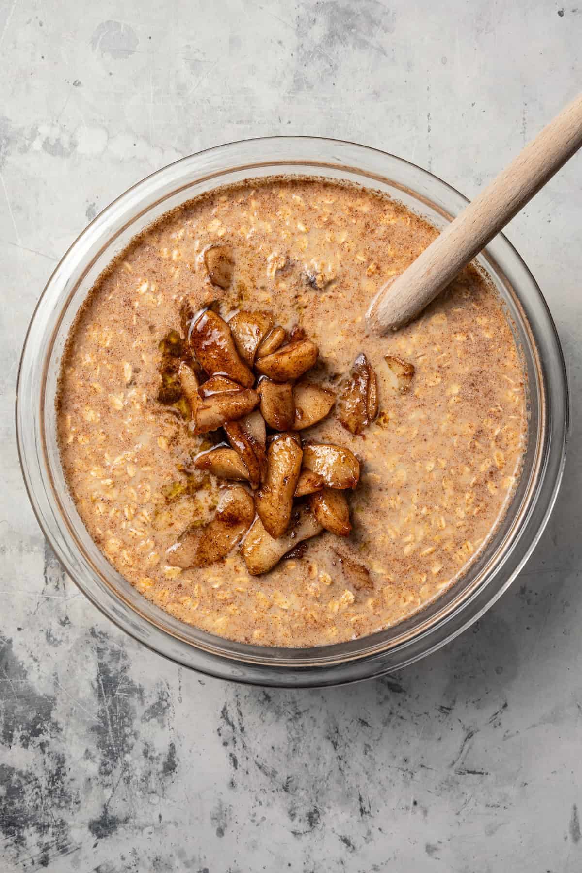 Cinnamon apples added to oatmeal in a mixing bowl.