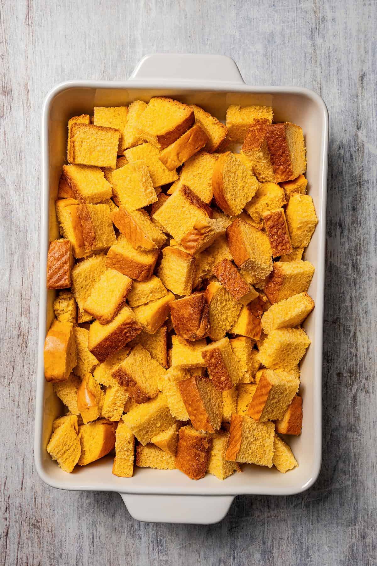 Brioche bread cubes added to a baking dish.