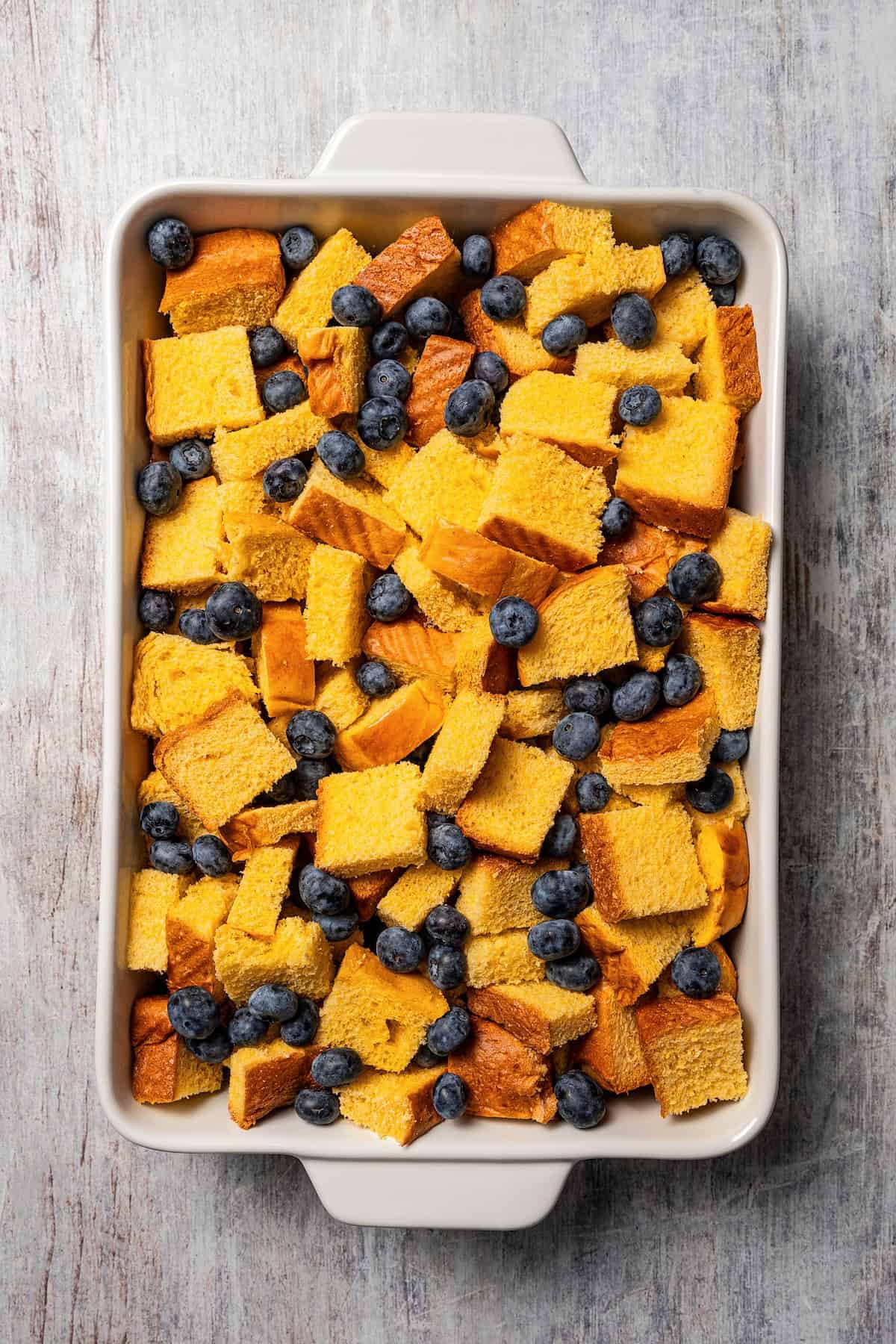 Bread cubes and blueberries combined in a baking dish.