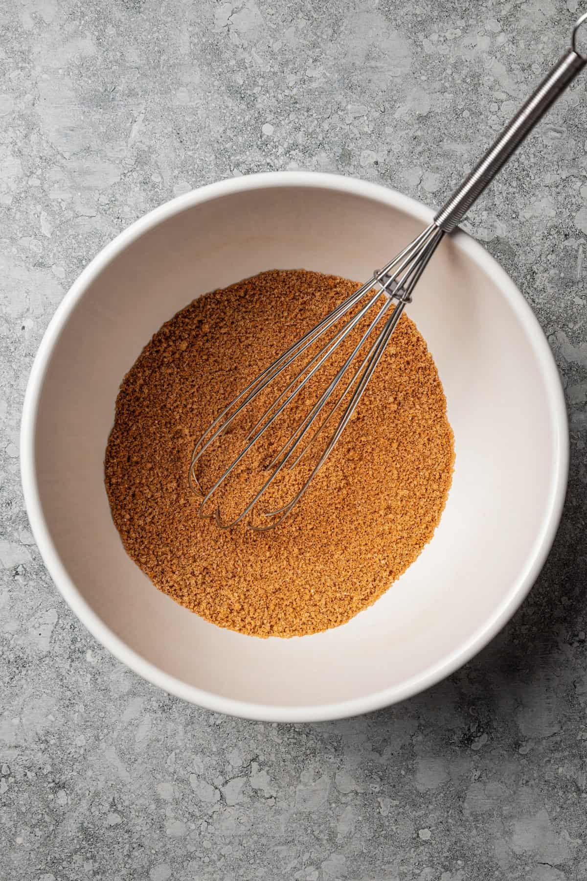Cinnamon roll filling in a bowl with a whisk.