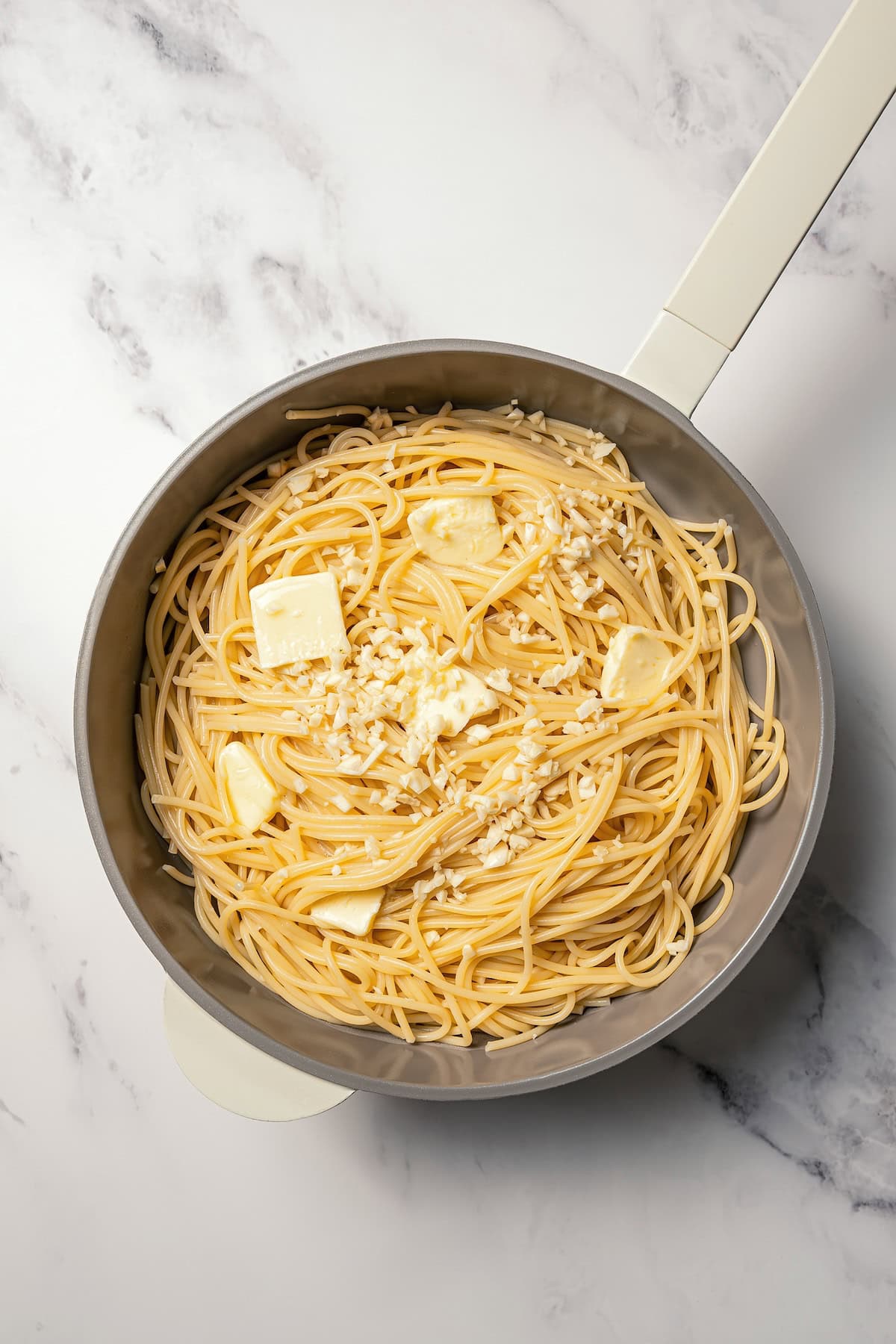 Make saucy garlic butter noodles in 15 minutes! You can adapt this easy recipe with shrimp, chicken, or veggies for a quick weeknight dinner. Butter and garlic added to warm spaghetti in a skillet.