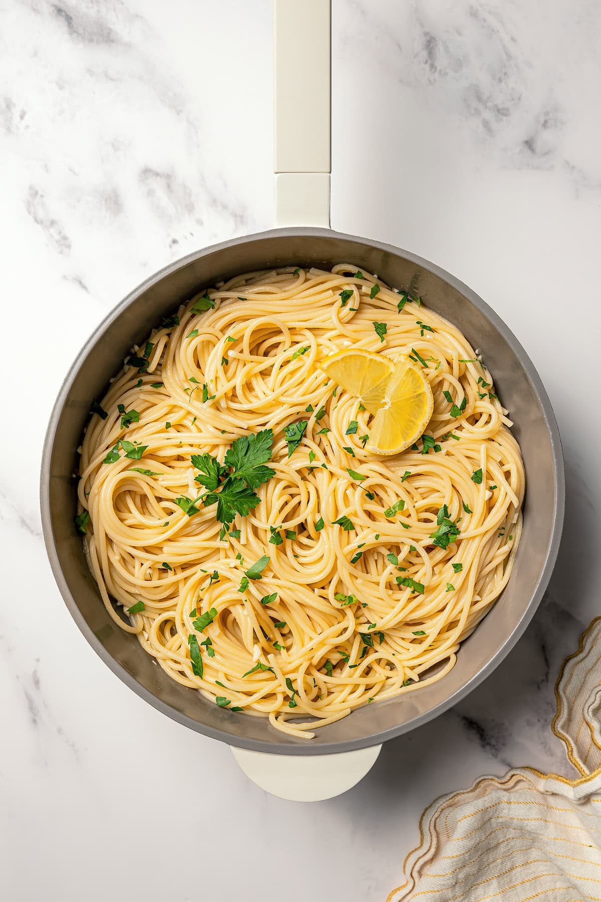 Make saucy garlic butter noodles in 15 minutes! You can adapt this easy recipe with shrimp, chicken, or veggies for a quick weeknight dinner. Garlic butter noodles garnished with fresh parsley and a lemon wedge in a skillet.