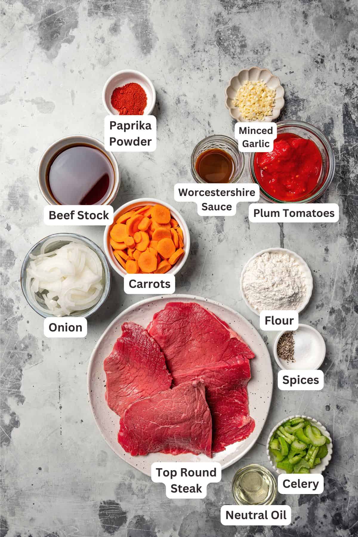 This Swiss steak recipe with gravy is a comforting dinner with juicy beef slow-braised in a rich tomato sauce and served over mashed potatoes. Swiss steak ingredients with text labels overlaying each ingredient.
