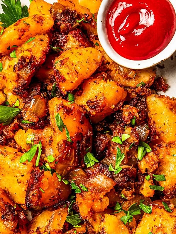 Overhead view of breakfast potatoes served on a large oval platter with a side of ketchup.