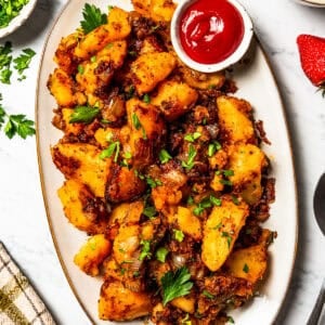Overhead view of breakfast potatoes served on a large oval platter with a side of ketchup.