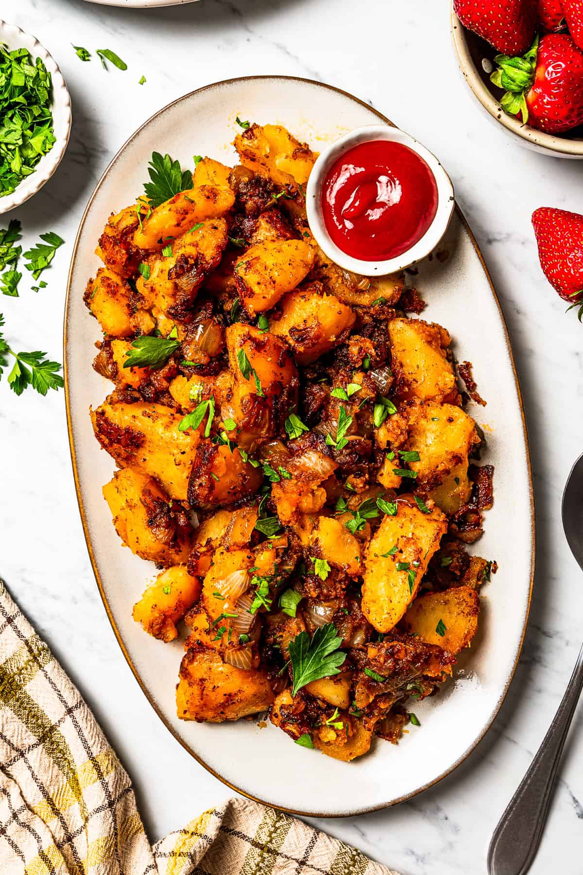 These seasoned and crispy breakfast potatoes are boiled, pan-fried, and finished in the oven so they're fluffy inside with golden-brown edges. Overhead view of breakfast potatoes served on a large oval platter with a side of ketchup.