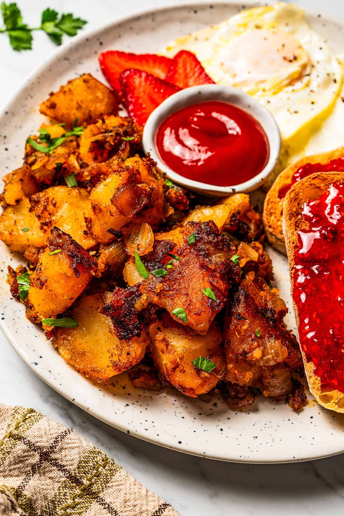These seasoned and crispy breakfast potatoes are boiled, pan-fried, and finished in the oven so they're fluffy inside with golden-brown edges. Diced potatoes served with ketchup on a plate.