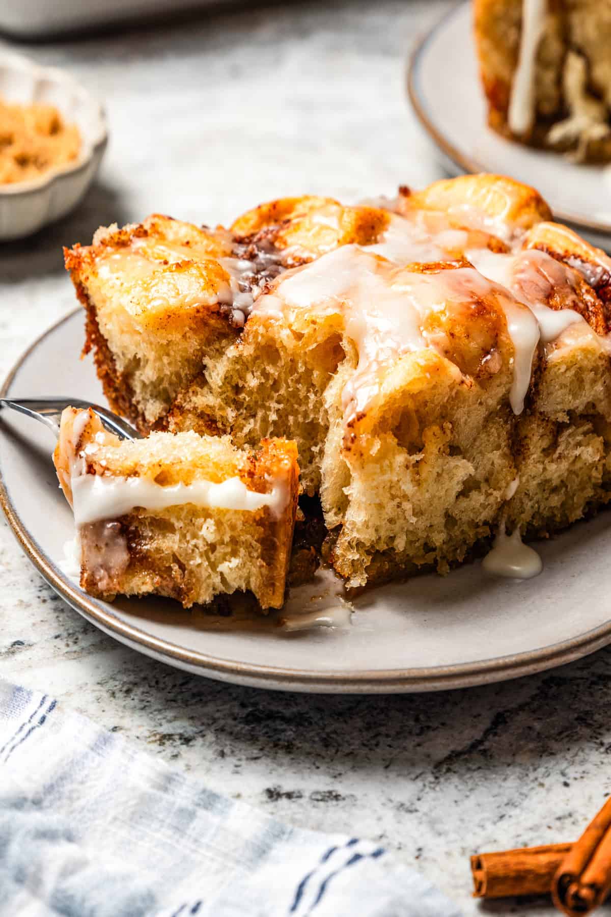 A fork breaking out a bite from a slice of cinnamon roll casserole.
