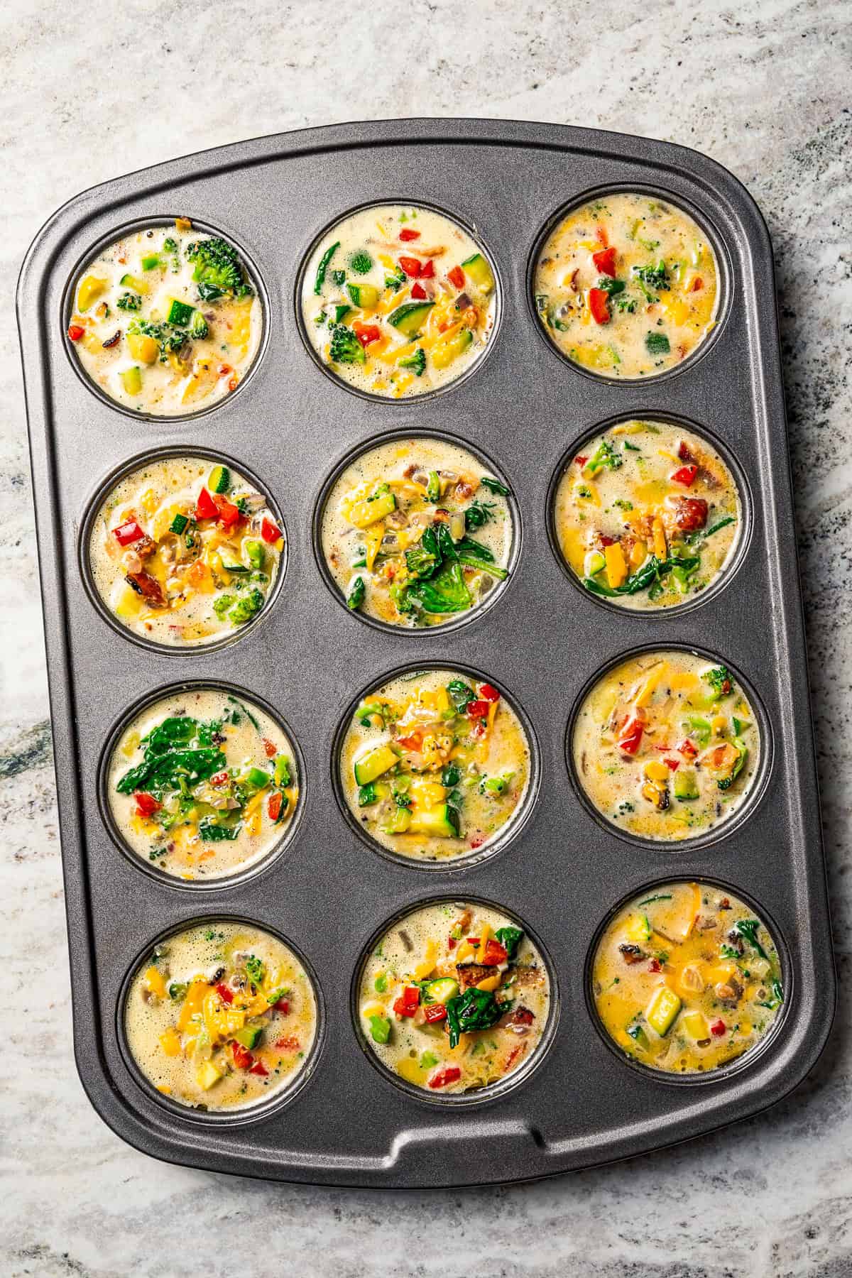 Egg mixture poured into the cups of a muffin pan to make egg bites.