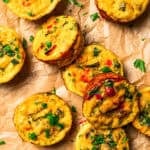 Several egg bites are arranged on a parchment paper-lined surface.