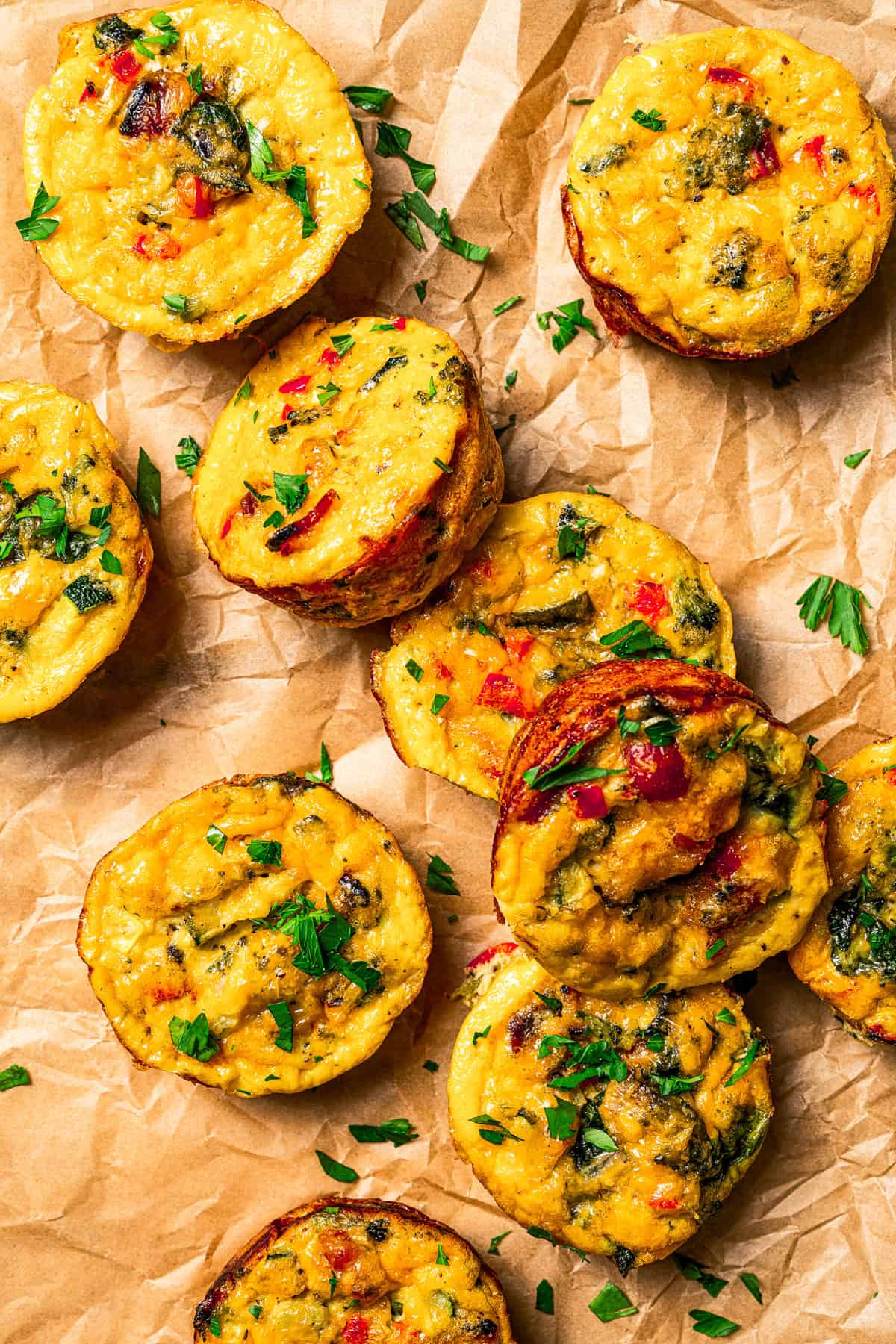 Several egg bites are arranged on a parchment paper-lined surface.