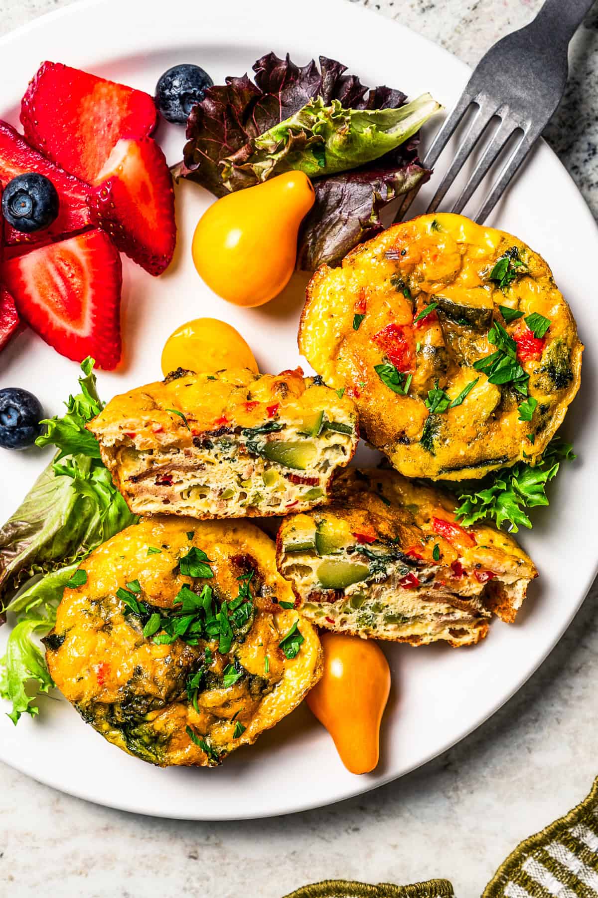 Egg bites served on a plate with a side of salad greens and fresh berries.