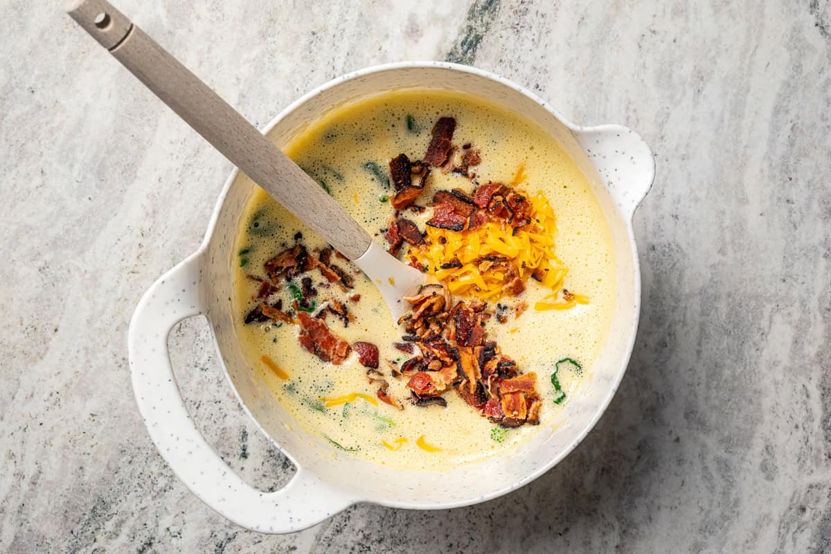 This Starbucks-inspired egg bites recipe with cottage cheese and veggies is quick to bake in a muffin tin. It's an easy, on-the-go breakfast! Egg bite mixture combined with bacon and veggies in a mixing bowl.