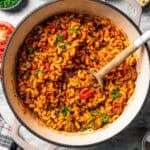 Goulash in a pot with a wooden spoon stirring through it.