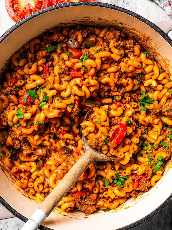 Goulash in a pot with a wooden spoon stirring through it.