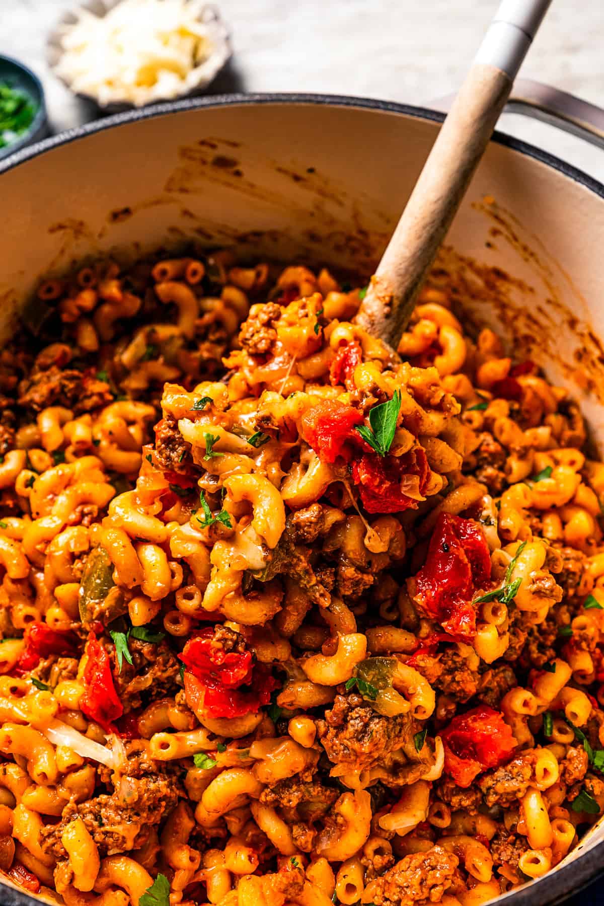 A spoon scooping goulash from a large pot.