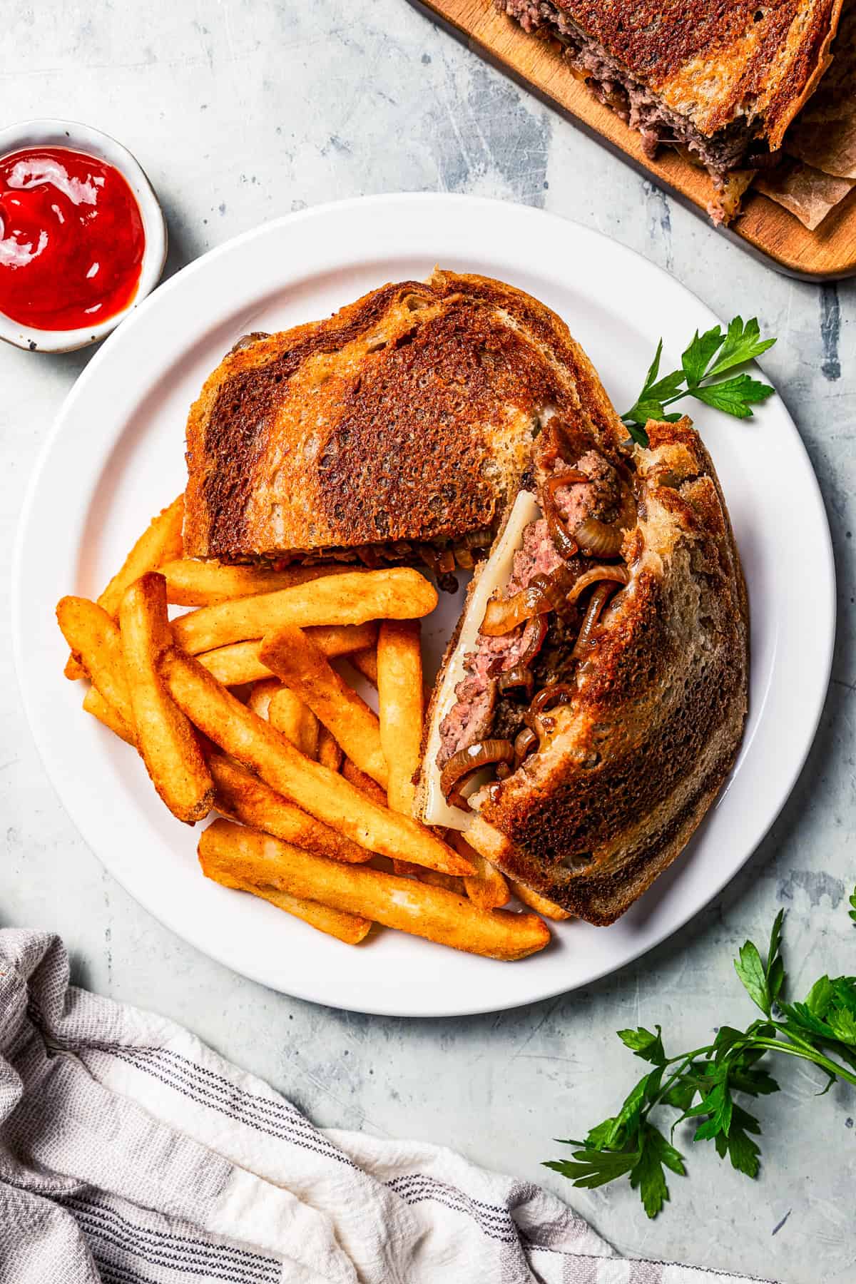 Patty melt on a plate with French fries.