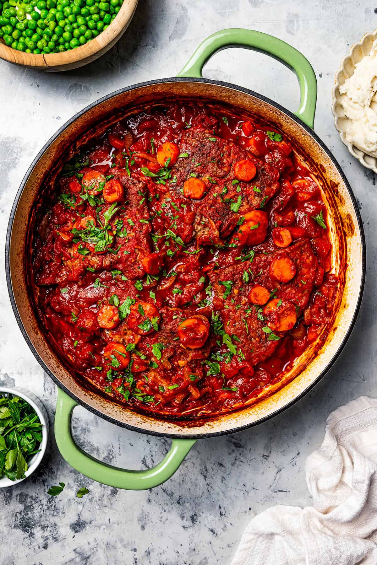 This Swiss steak recipe with gravy is a comforting dinner with juicy beef slow-braised in a rich tomato sauce and served over mashed potatoes. Steaks in tomato sauce in a Dutch oven.