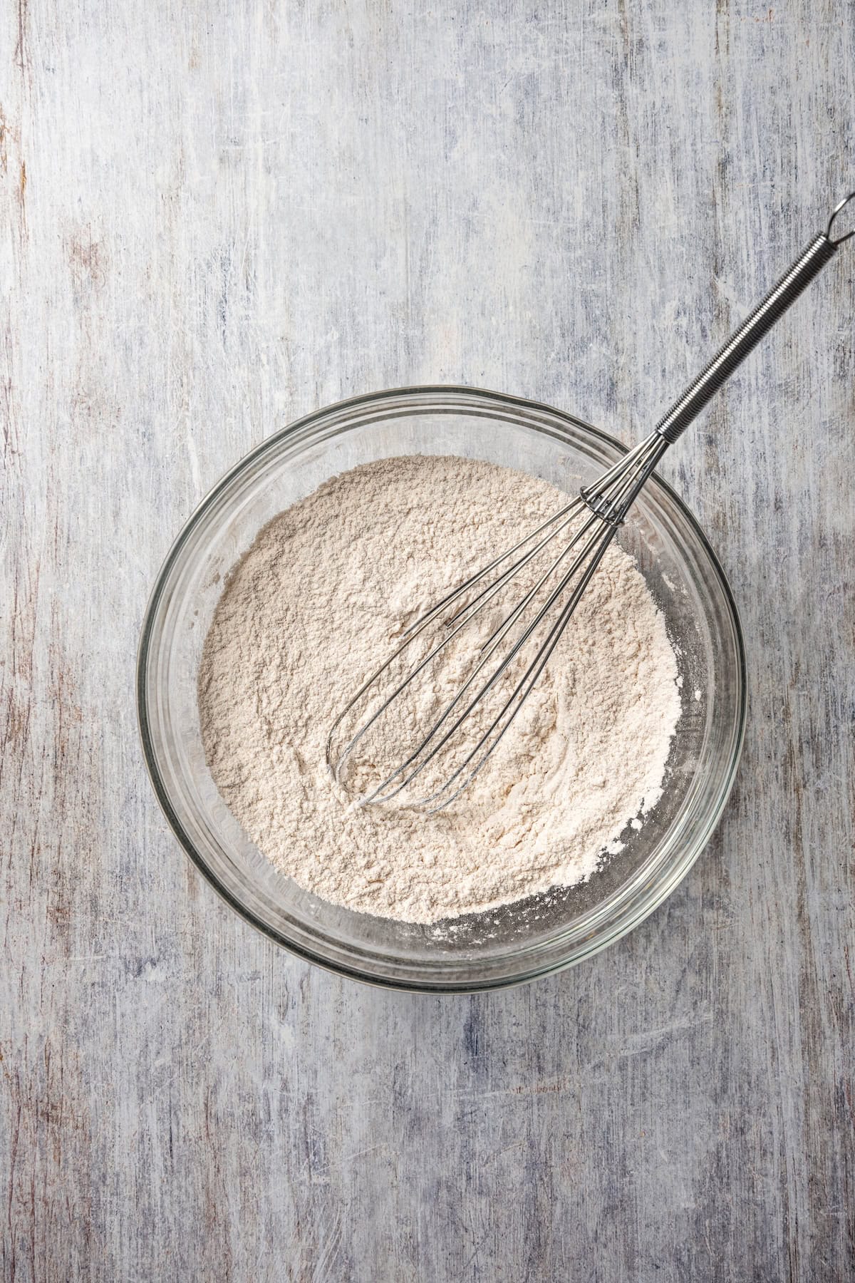 These easy, soft-baked sweet potato cookies are made with sweet potato purée, fall spices, and stuffed with sweet cream cheese in the middle! Dry ingredients combined in a bowl with a whisk.