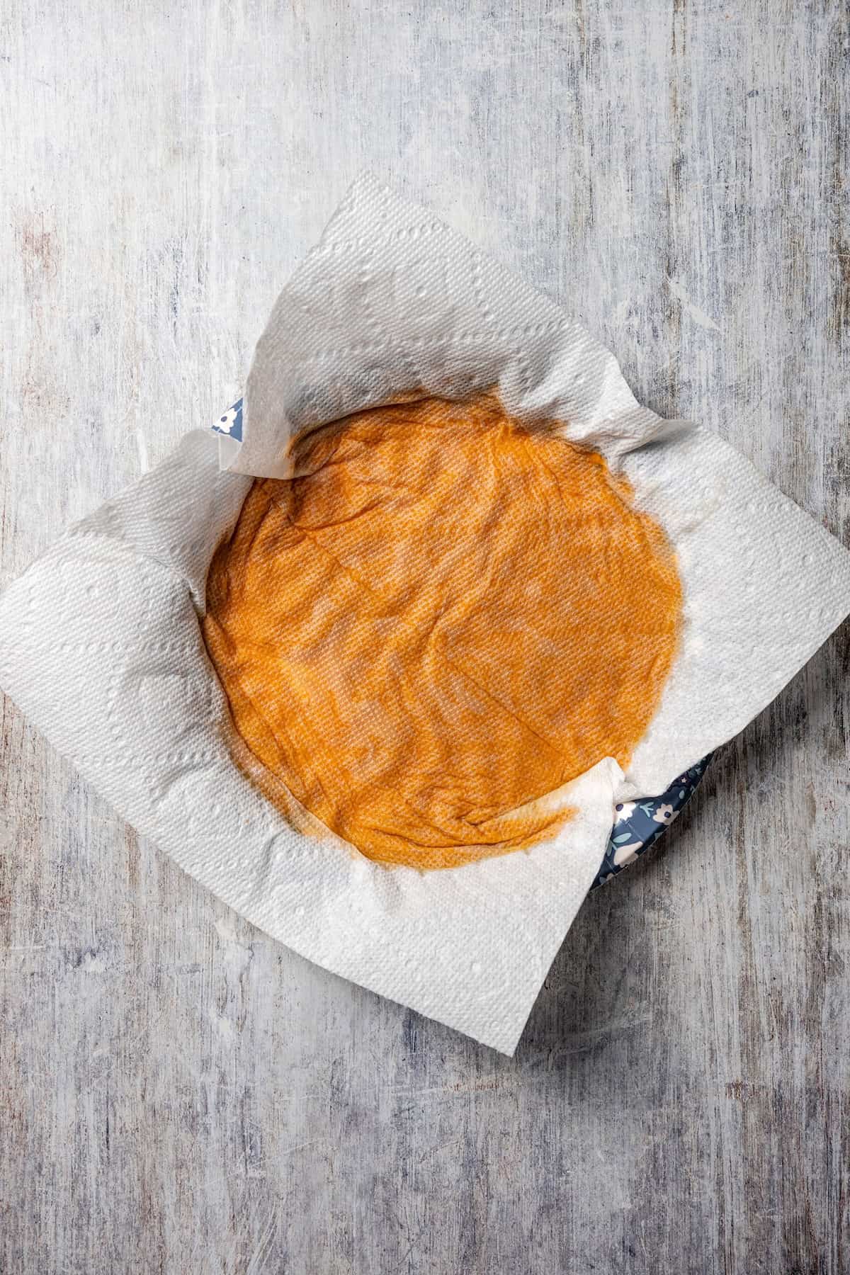 These easy, soft-baked sweet potato cookies are made with sweet potato purée, fall spices, and stuffed with sweet cream cheese in the middle! Paper towel being used to press the excess moisture from sweet potato purée.